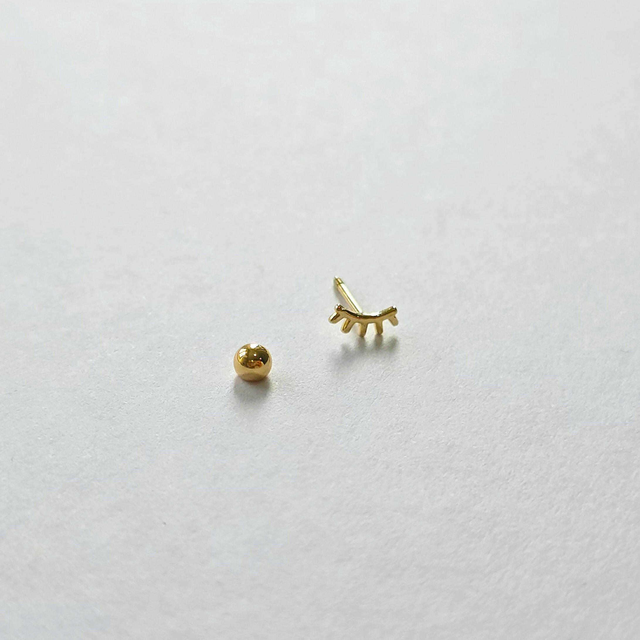 Screwball back and post detail on gold eyelash cartilage stud