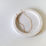Ally Chain Anklet displayed on a soft light pink tray, highlighting its subtle shimmer and delicate chain