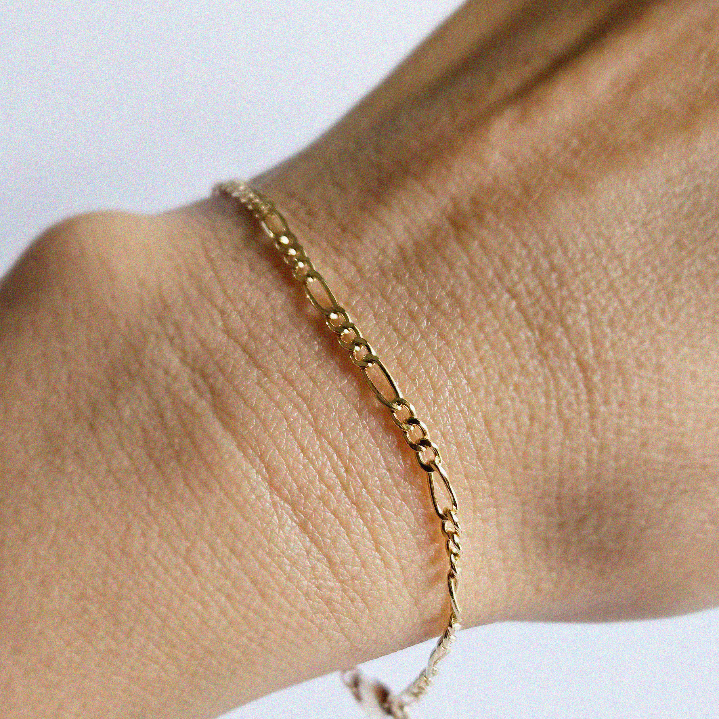 Top view of wrist styling with thicker Figaro gold bracelet