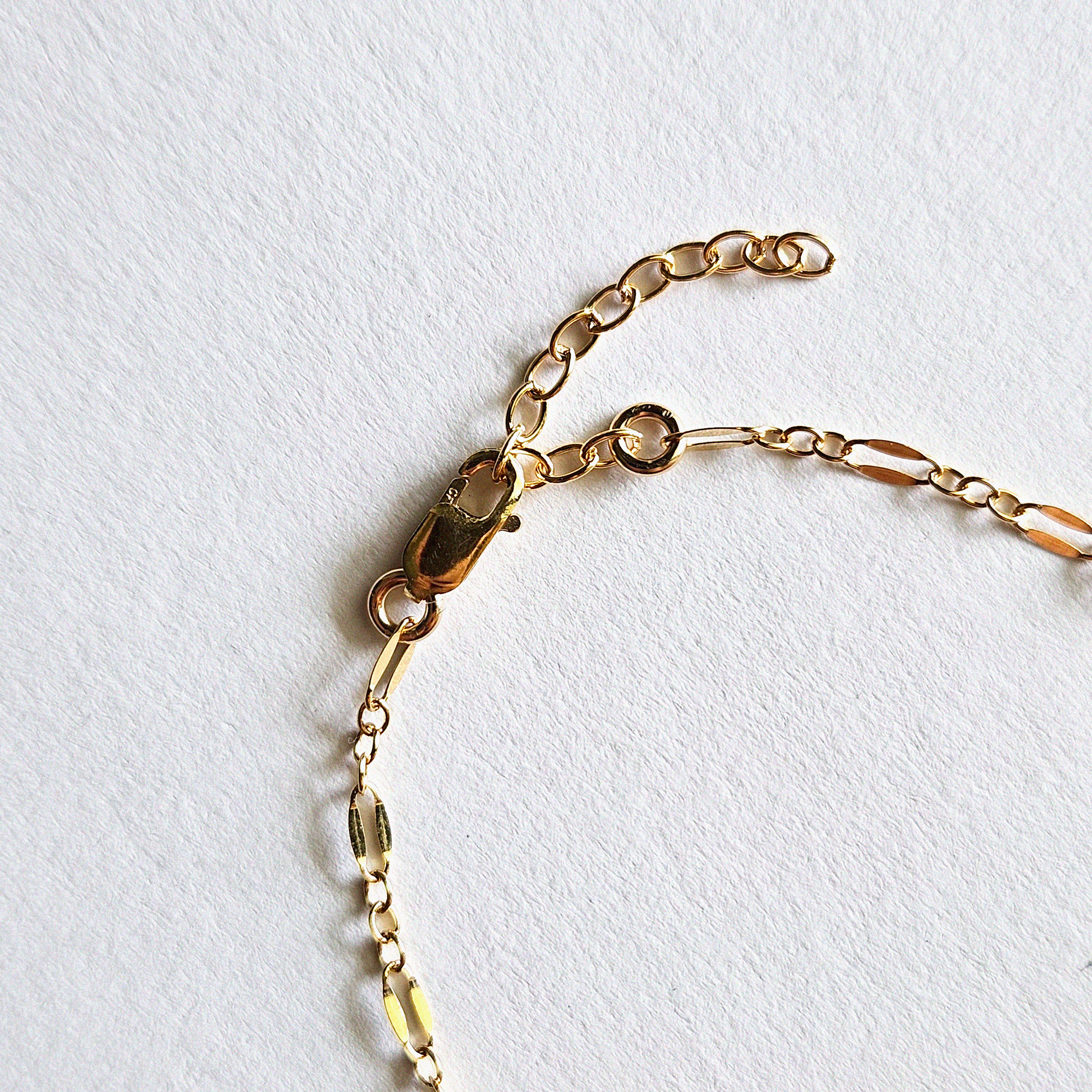 Zoomed-in image of lobster clasp and extension chain on coffee bean bracelet