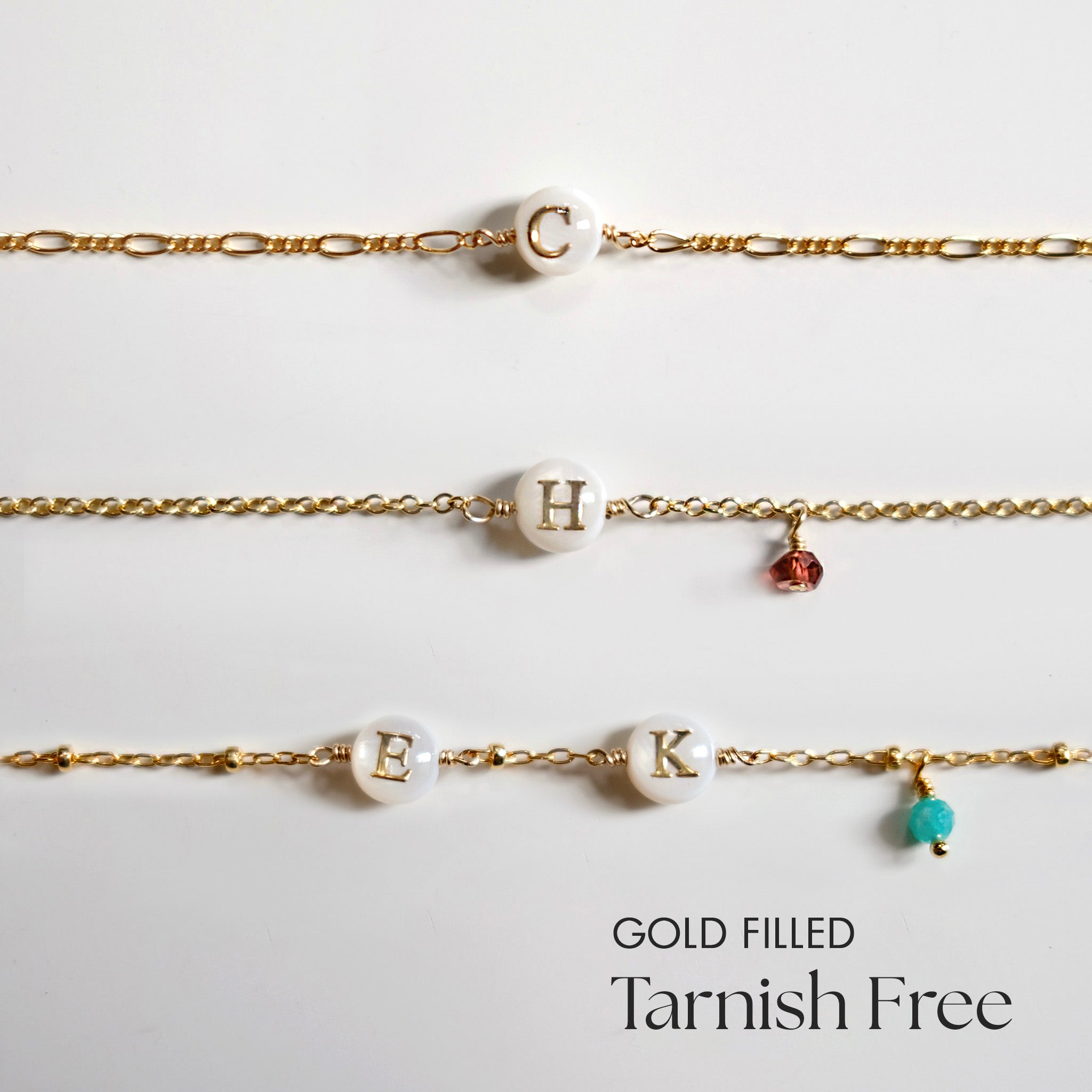Three gold filled bracelets with letter beads on a light gray background