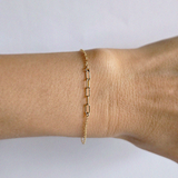 Minimal gold bracelet worn solo highlighting central chain