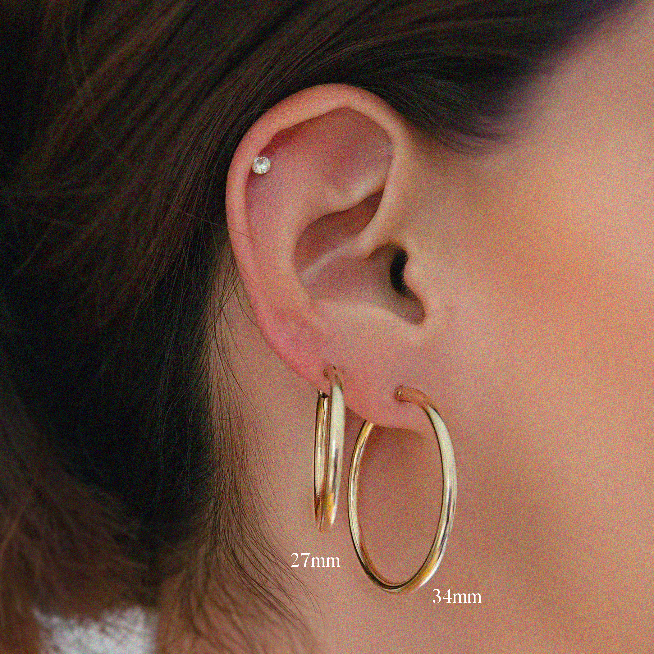 Model showcases gold-filled flex hoops in 27mm and 34mm to highlight size differences