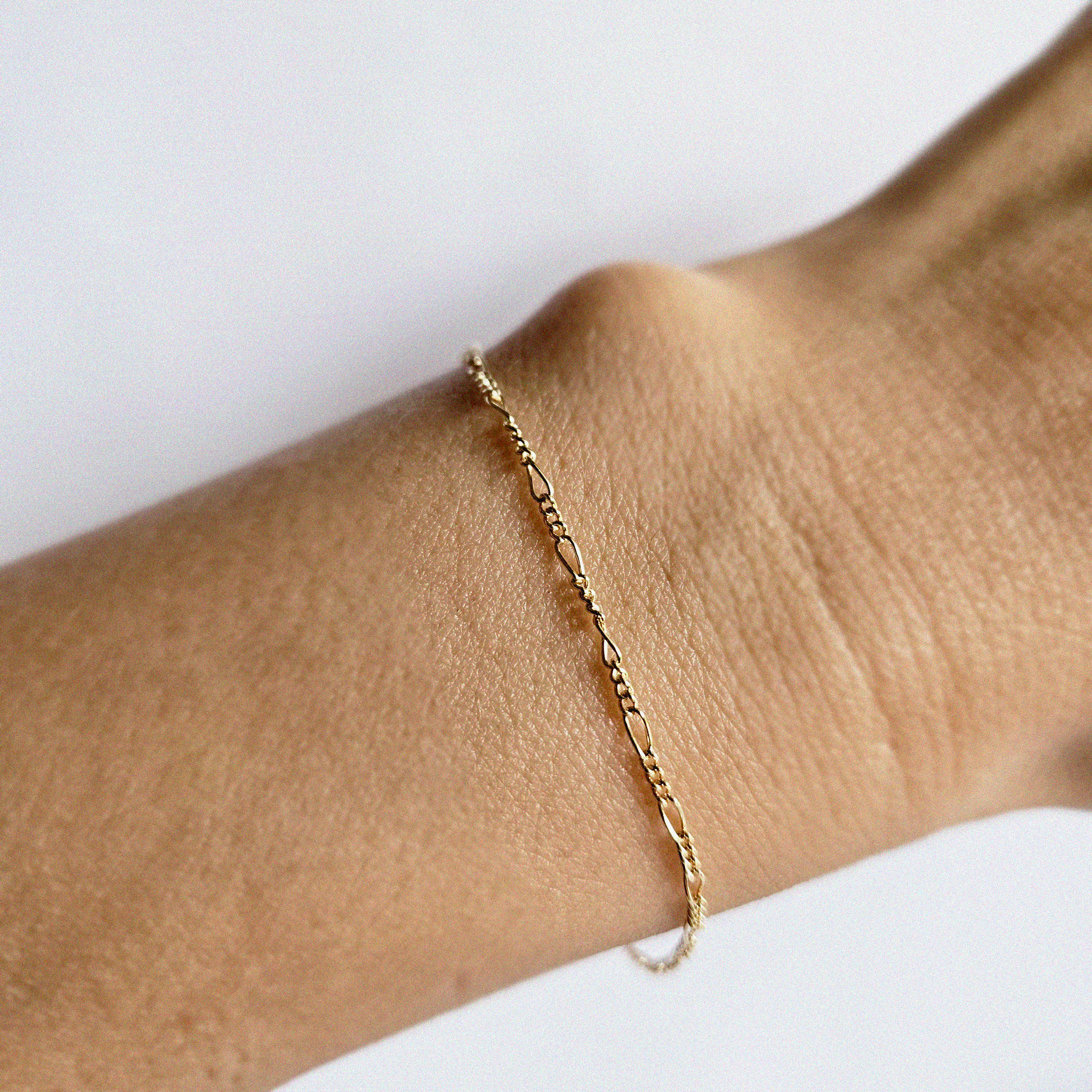 Minimal gold chain bracelet worn on wrist, viewed from the top