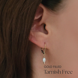 Close-up ear shot showing pearl earring gently hanging from leverback clasp