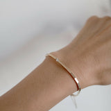 Minimalist diamond bracelet worn on wrist, capturing the sleek and polished gold finish