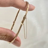 Close-up of the Grazia Diamond Bracelet held between fingers, showing the secure clasp and safety chain