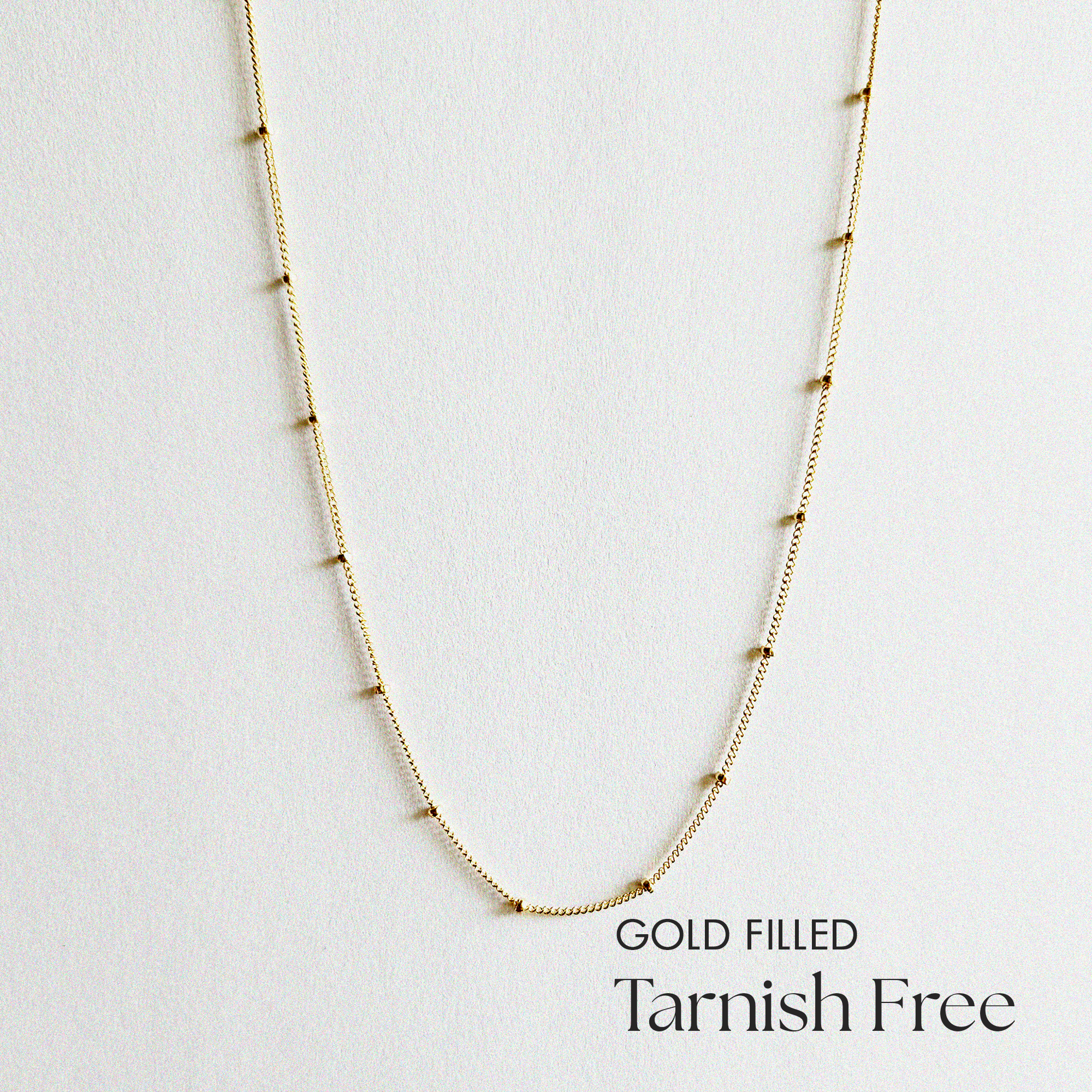 Gold filled dotty chain necklace laid flat, showing delicate ball accents