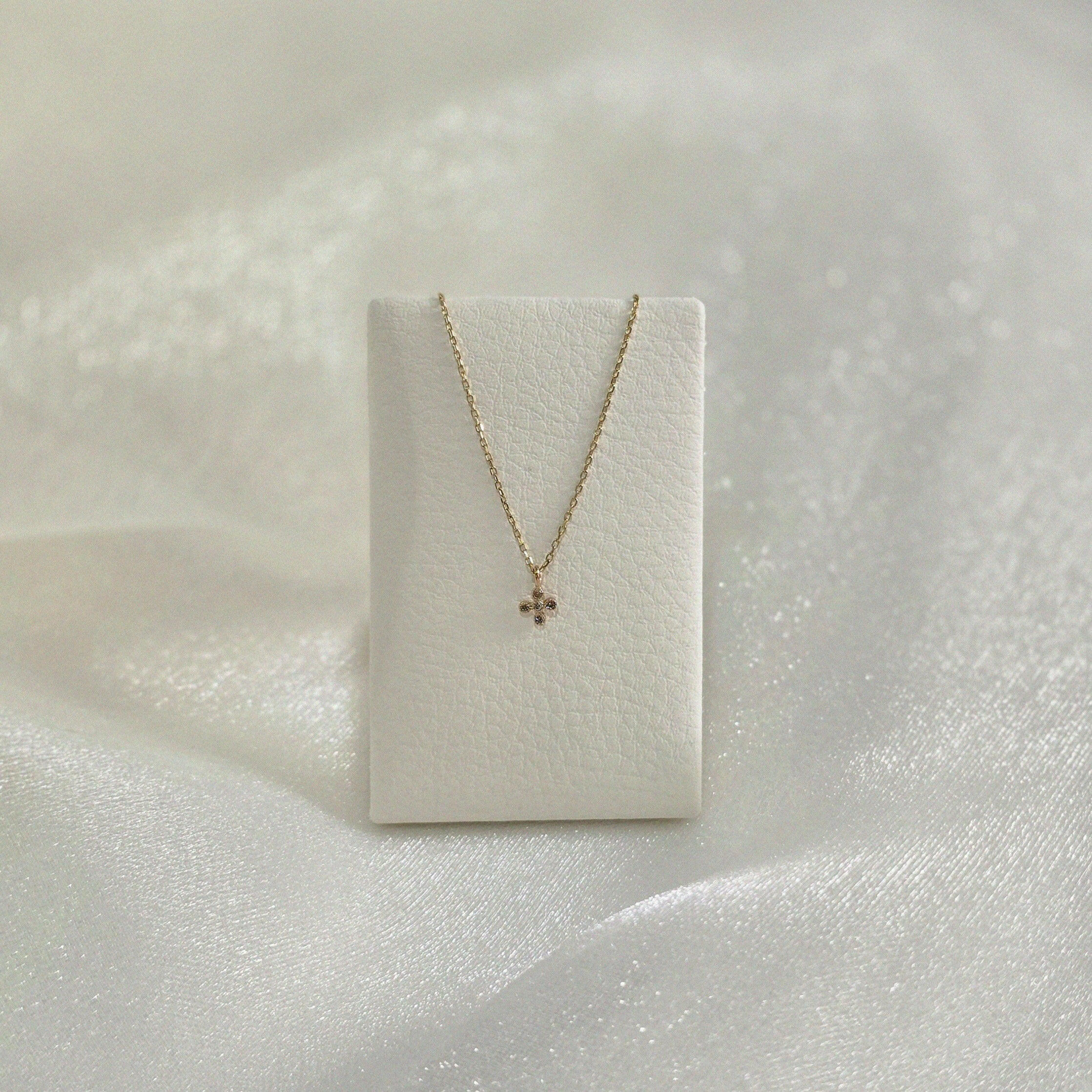 La Cross Diamond Necklace displayed on a soft white leather necklace holder, highlighting its graceful drape