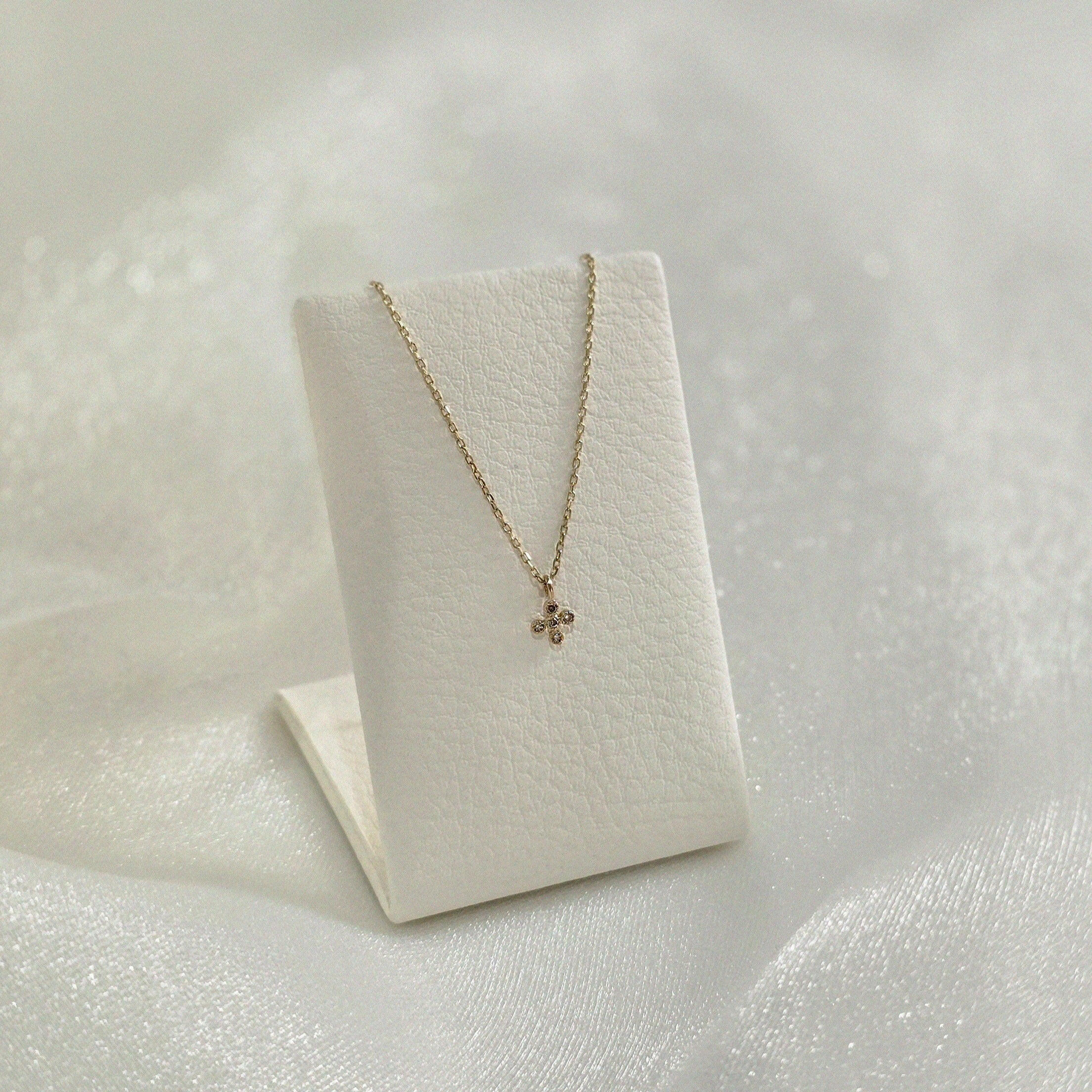 Diamond cross pendant showcased upright on a jewelry stand