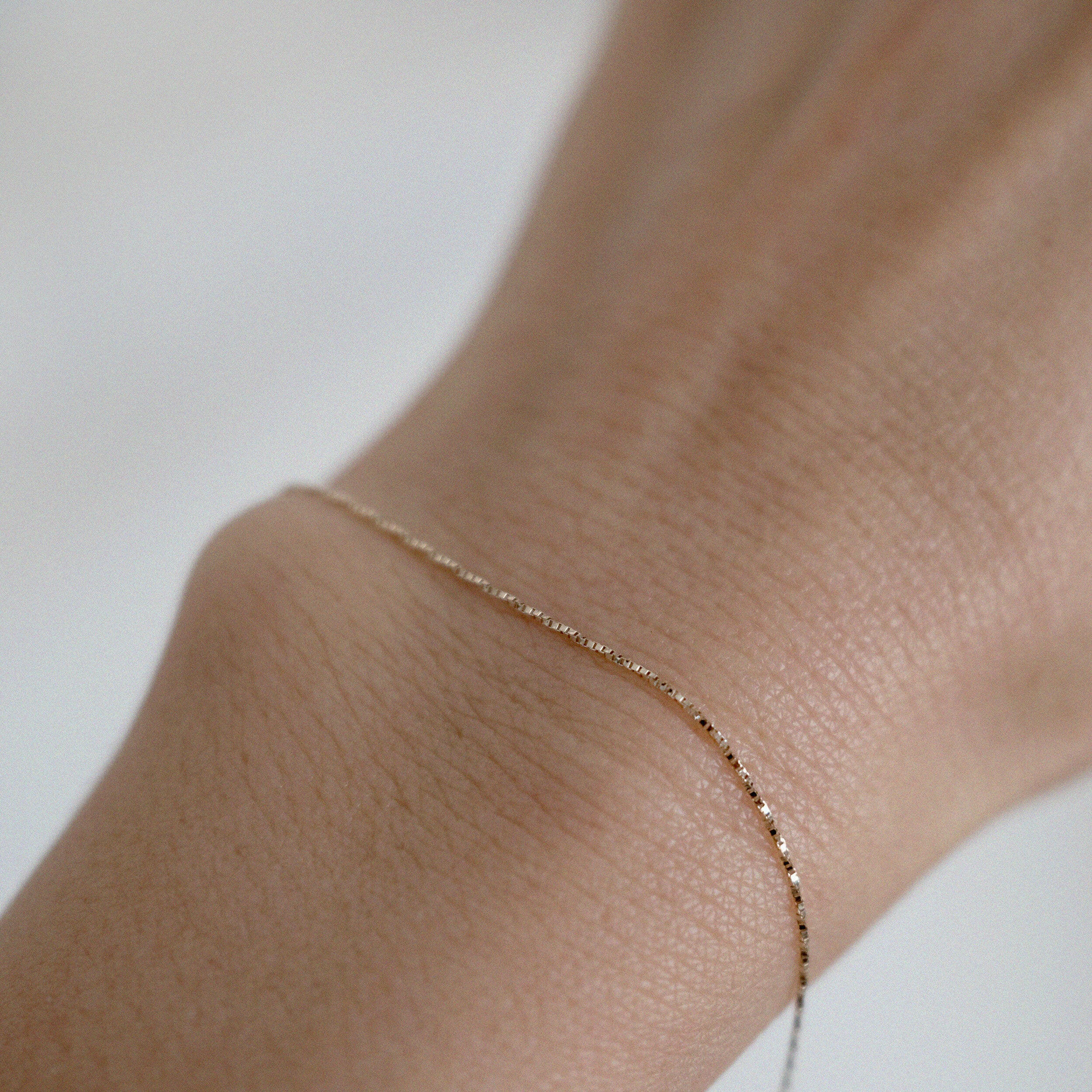 Model wearing the Lille Chain Bracelet alone on wrist, showing subtle glow