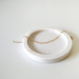 Linked heart bracelet draped naturally on soft neutral-toned jewelry tray