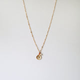 Gold filled necklace with shell pendant, pearl, and coral beads laid fla