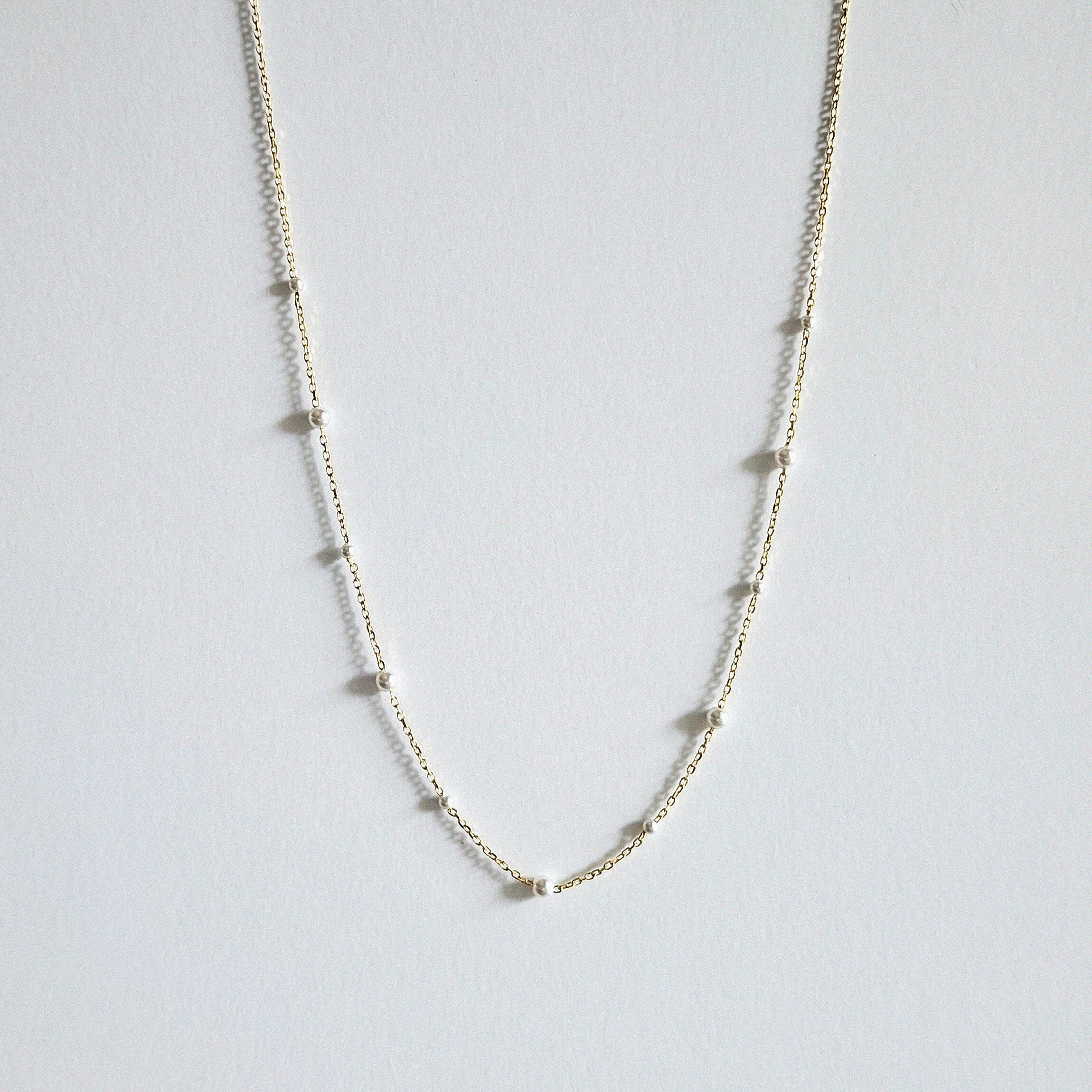 Mixed pearls necklace laid flat, showing graduated Swarovski pearls on a delicate gold chain