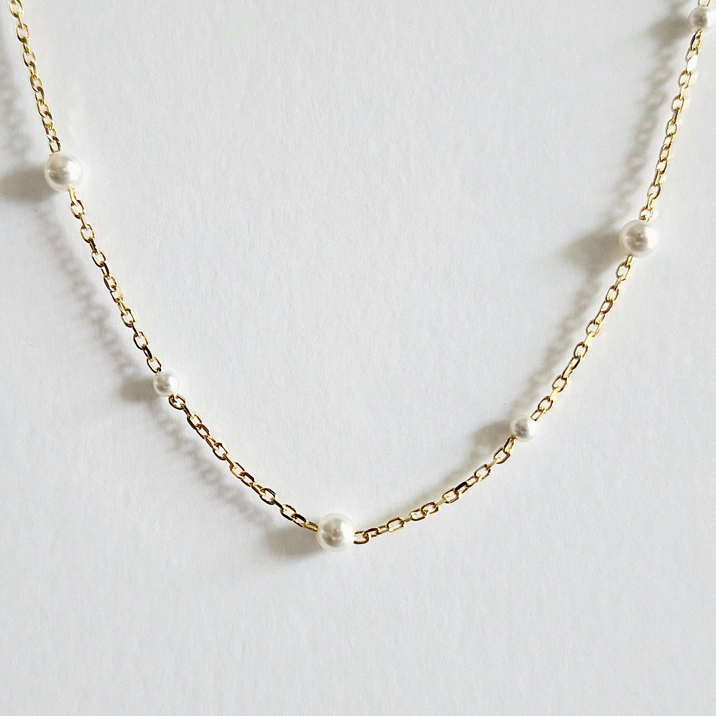 Zoomed-in view capturing pearl surface and gold chain texture with soft shine