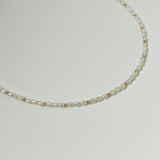 Close-up shot of freshwater pearl and gold bead detail against white background