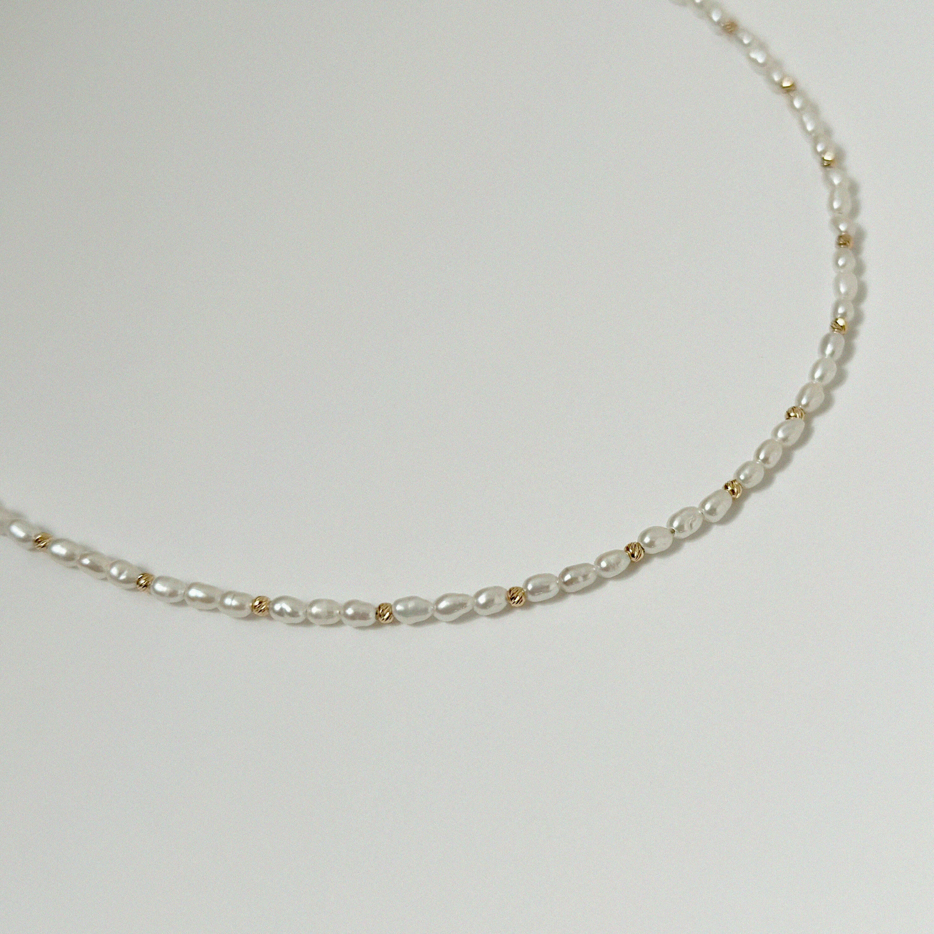 Close-up shot of freshwater pearl and gold bead detail against white background