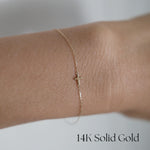 Model wearing the Petite Cross Bracelet alone on wrist for a delicate look