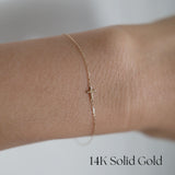 Model wearing the Petite Cross Bracelet alone on wrist for a delicate look