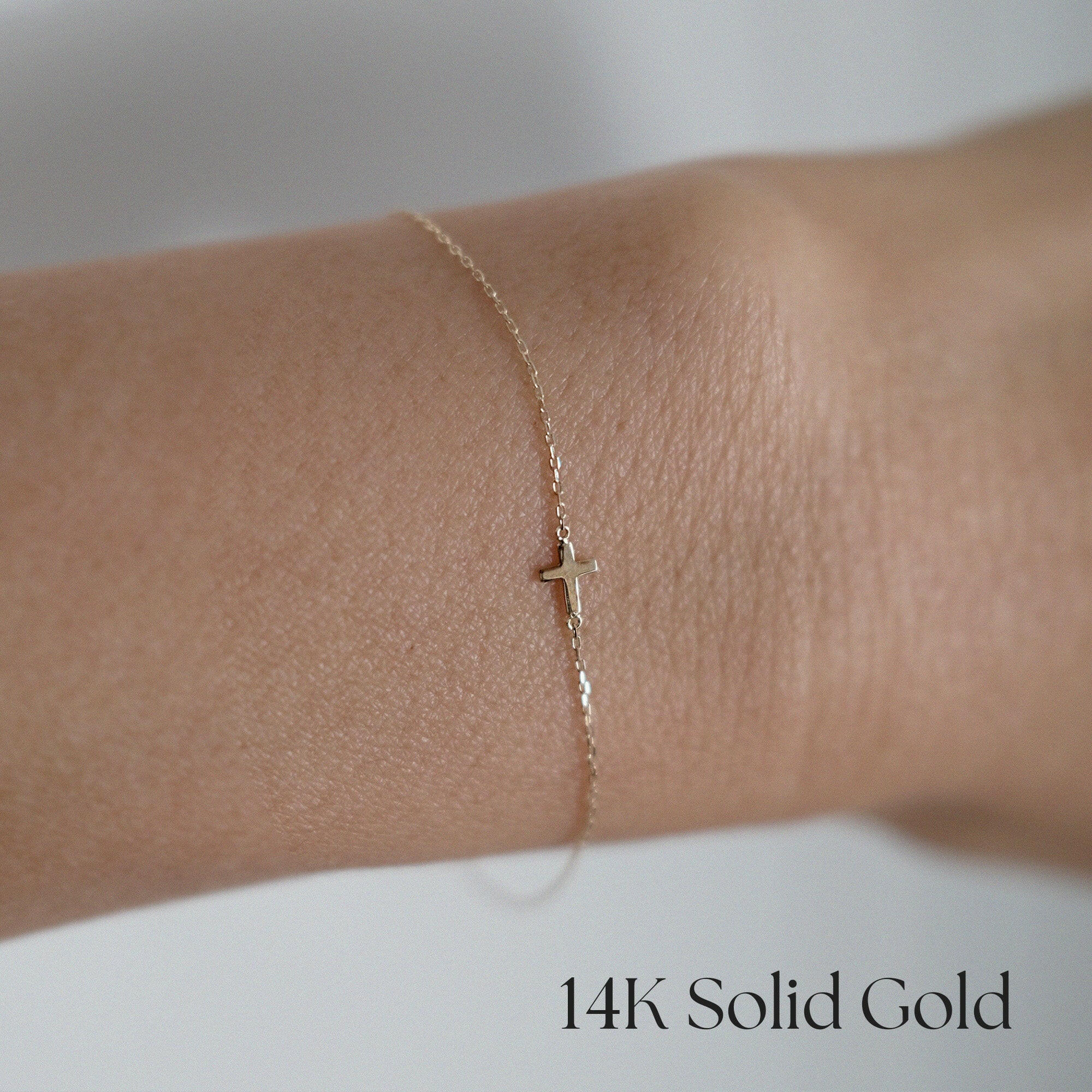 Model wearing the Petite Cross Bracelet alone on wrist for a delicate look