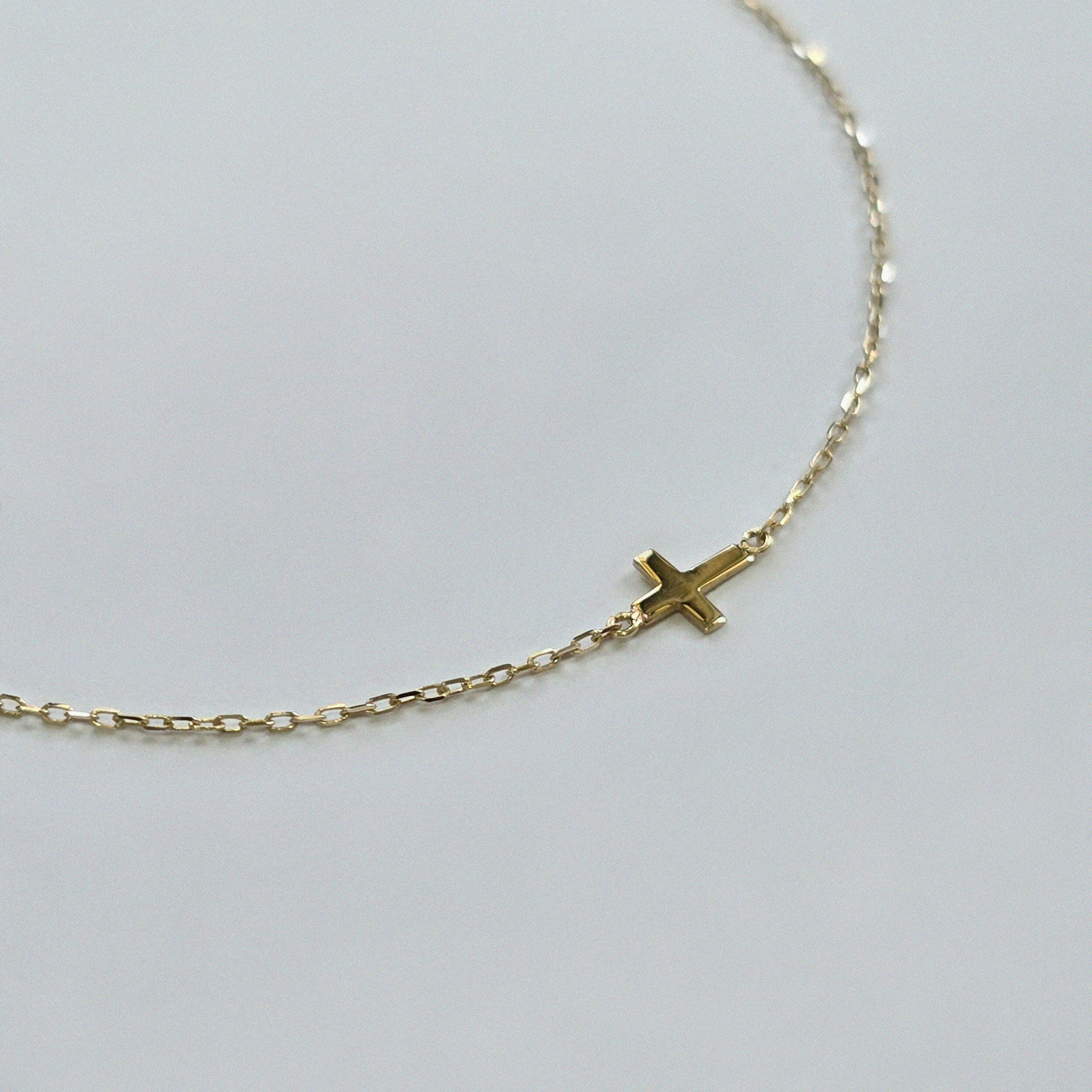 Minimalist gold bracelet featuring a 4mm x 5mm cross on a fine chain