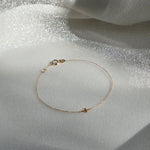 Petite Cross Bracelet displayed on shimmery textured fabric