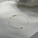 Petite Cross Bracelet displayed on shimmery textured fabric