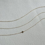 Minimalist gold bracelets with fine chain links laid flat on cream-colored textile background