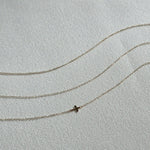 Minimalist gold bracelets with fine chain links laid flat on cream-colored textile background