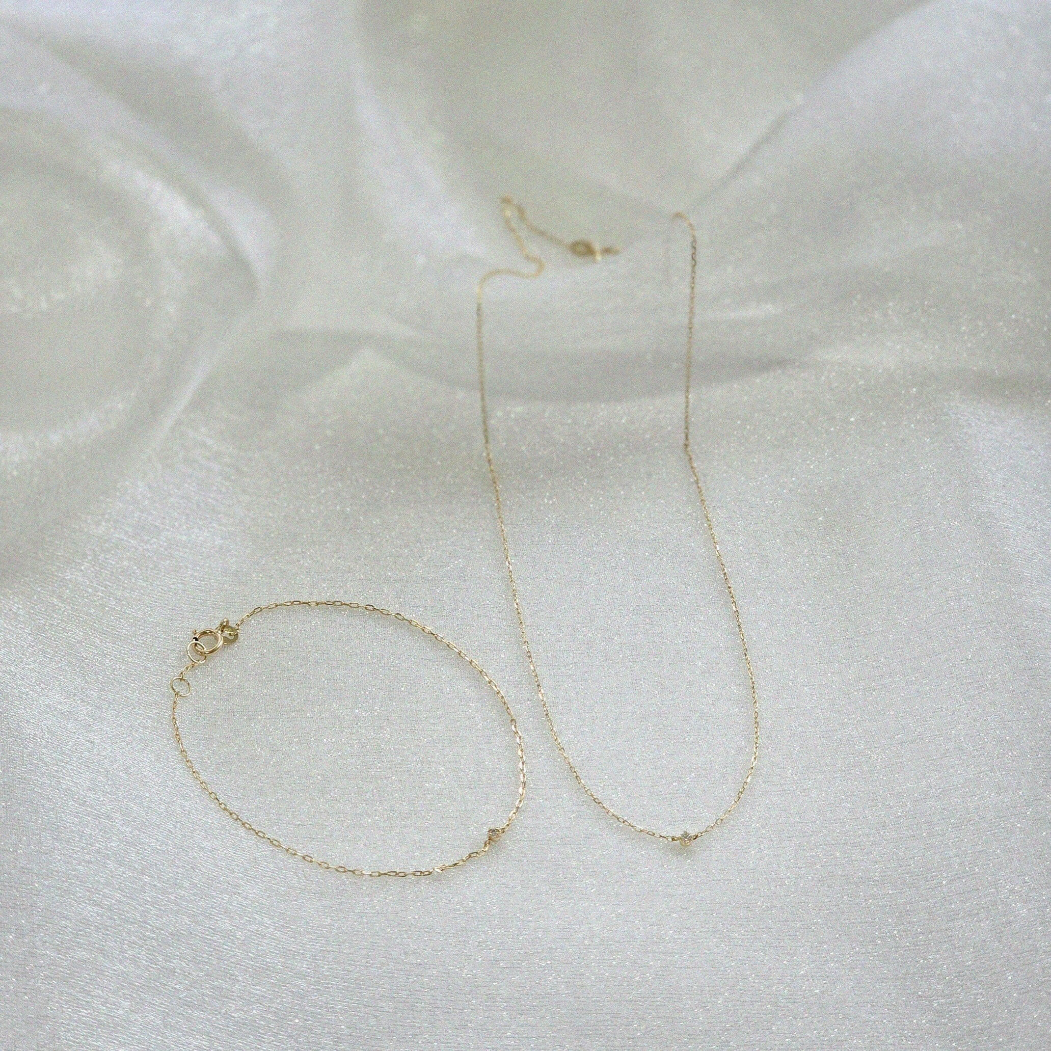 14K Petite Diamond Bracelet and matching necklace displayed on soft white satin fabric