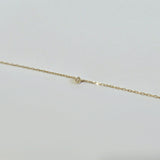 Detailed image of small brilliant diamond on a minimalist gold chain with polished finish