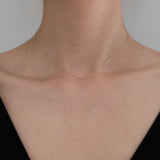 Model wearing petite diamond necklace with black off-shoulder top, close-up chest shot
