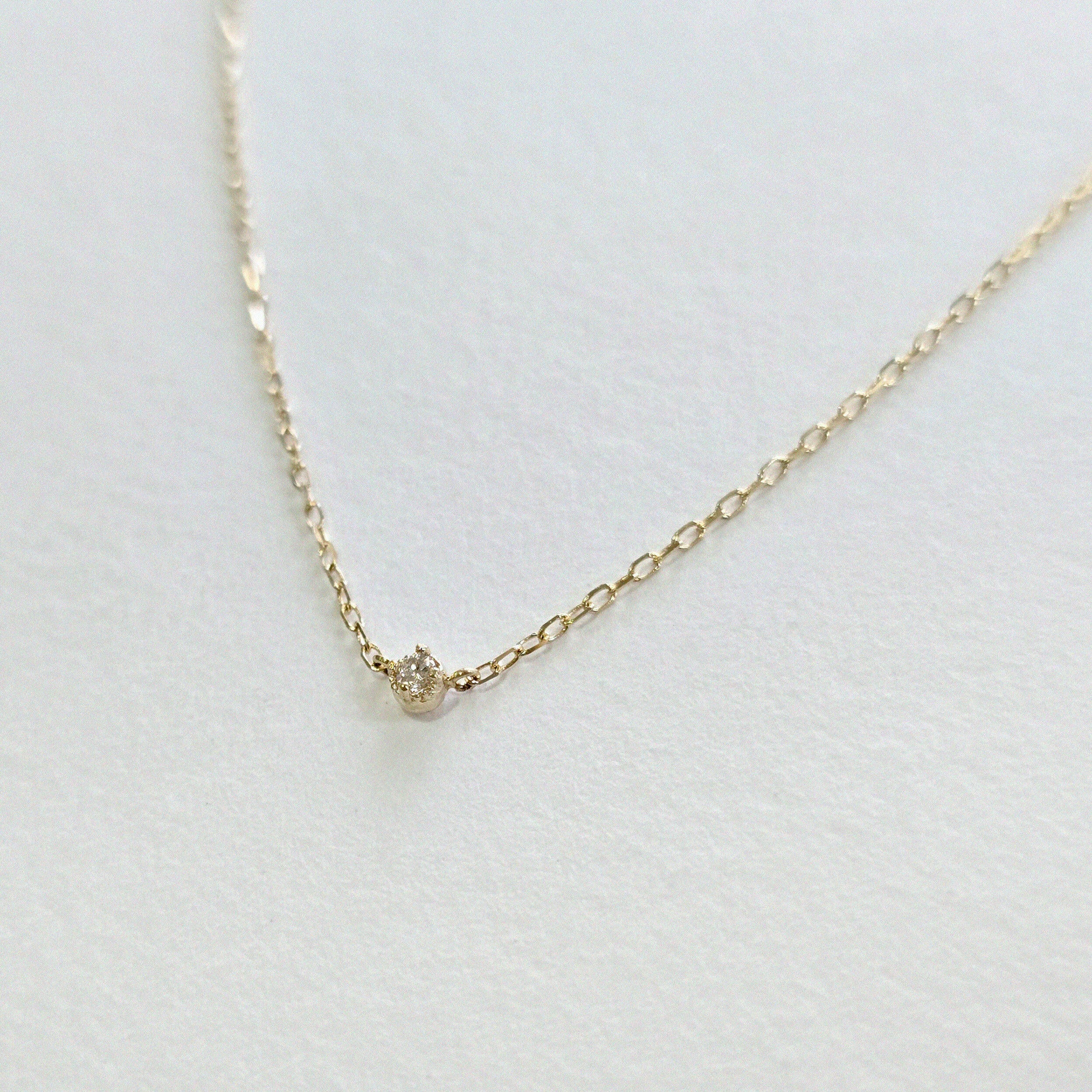Angled side view showing diamond depth and chain texture in 14K gold