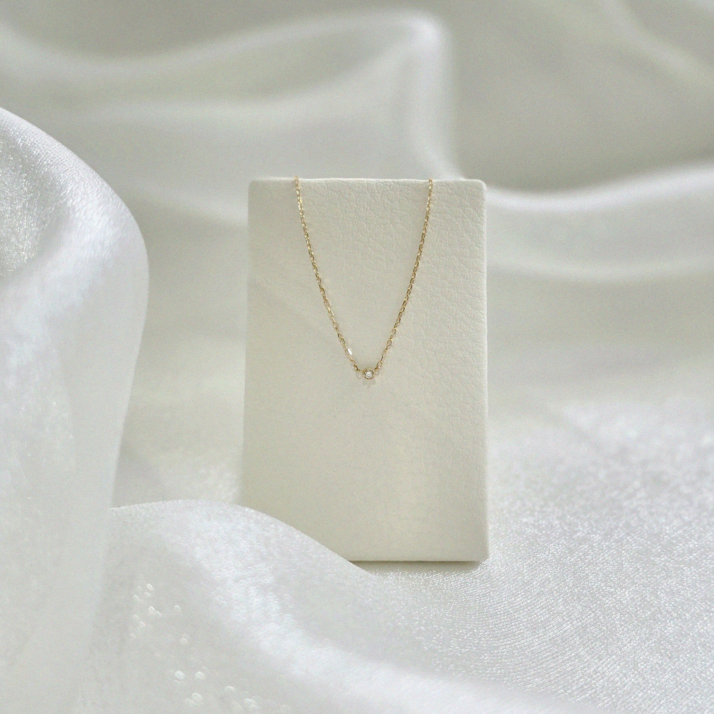 Petite Diamond Necklace displayed on cream leather necklace stand