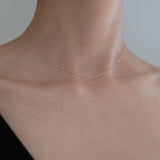 Model wearing petite diamond necklace with black V neck top, close-up chest shot