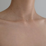 Model wearing Petite Pearl Necklace, pearl resting delicately at base of neck