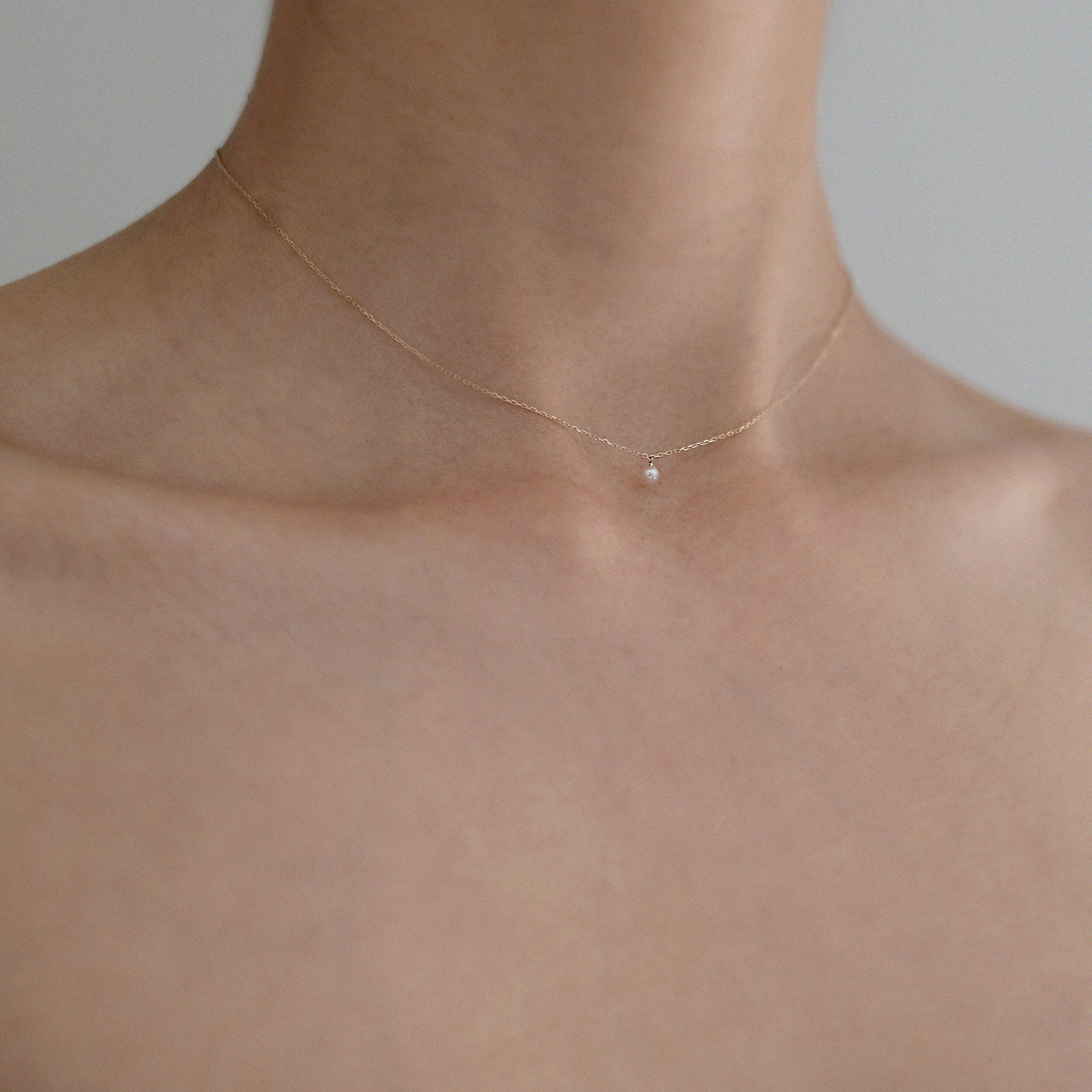 Model wearing Petite Pearl Necklace, pearl resting delicately at base of neck