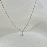 Angled shot of necklace showing chain delicacy and pearl depth from the side