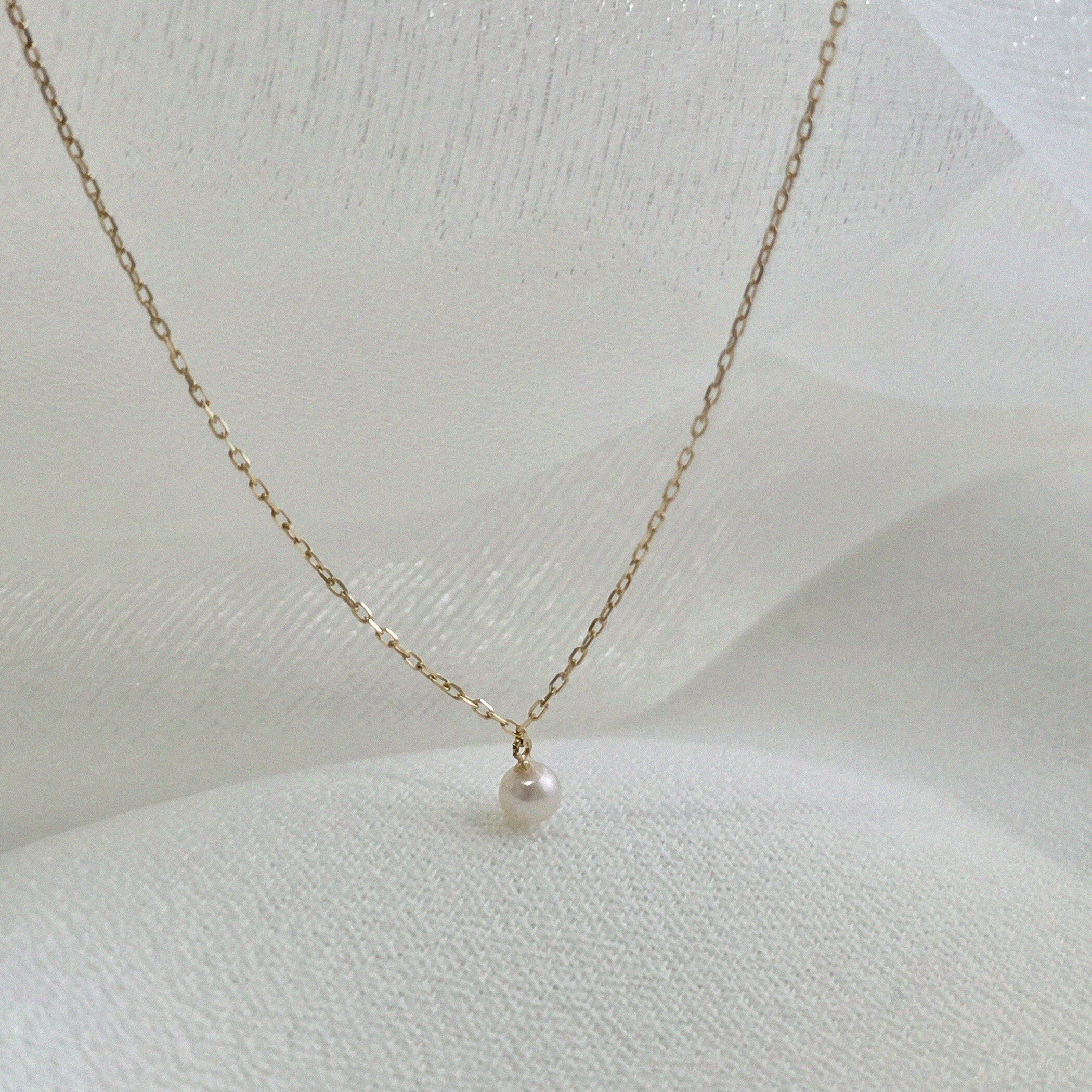 Angled shot of necklace showing chain delicacy and pearl depth from the side