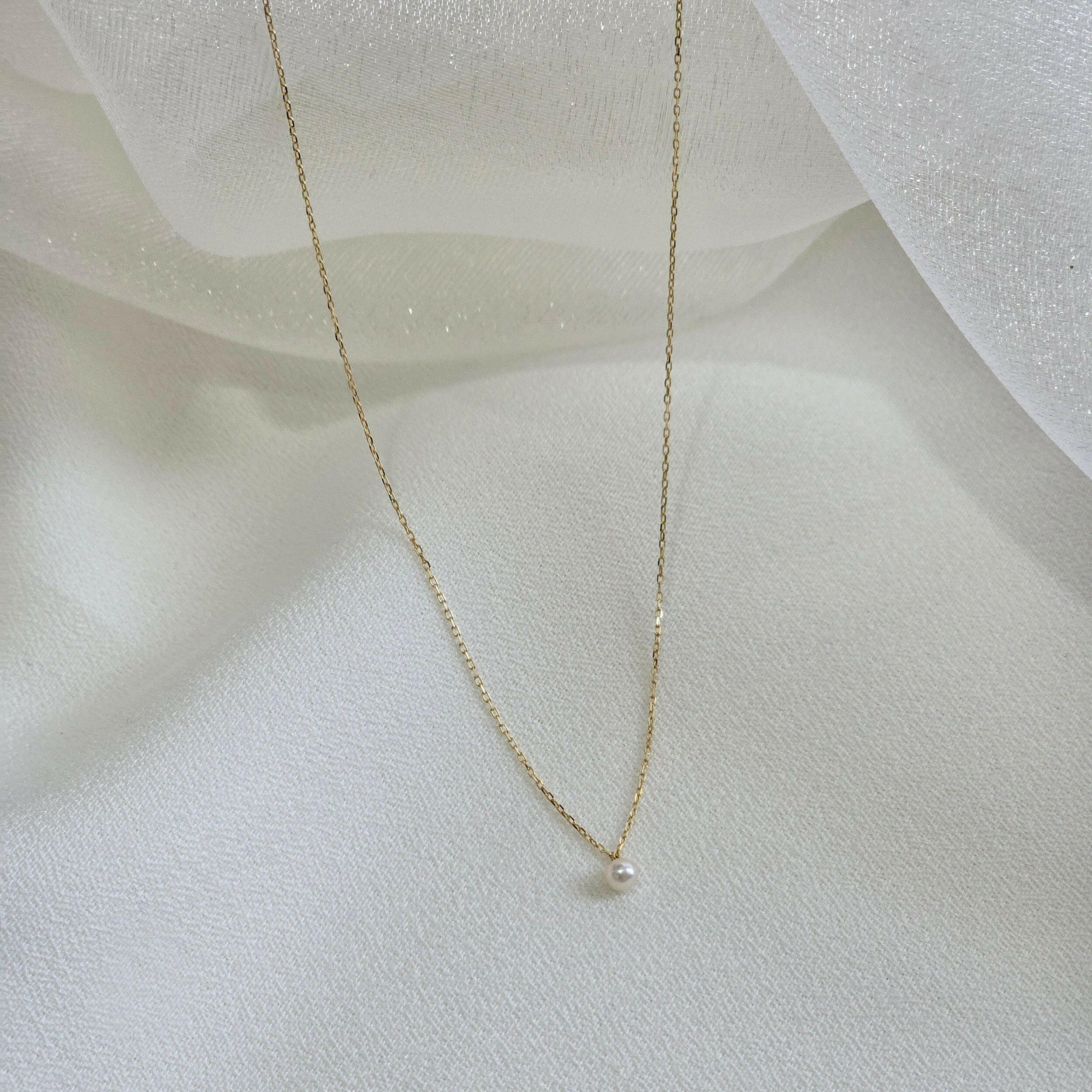 Side perspective capturing the gentle curve of the pearl and chain texture