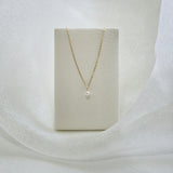 Petite Pearl Necklace draped on cream leather covered necklace stand, highlighting pendant drop