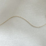 Close-up of the 14K Roma Chain Bracelet’s fine gold links displayed on soft satin fabric