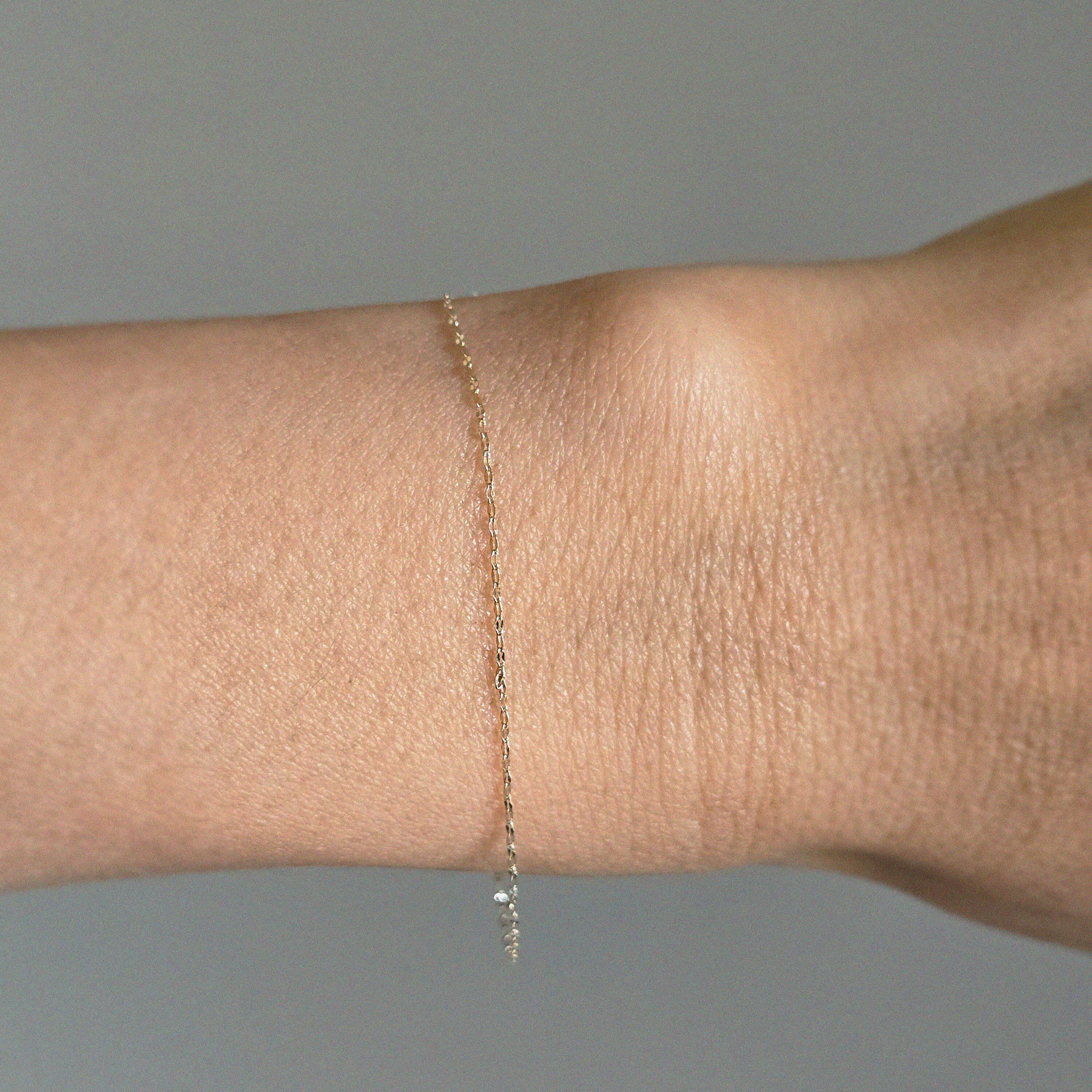 Ultra-thin gold bracelet styled casually on wrist with everyday attire
