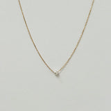Full view of the necklace laid out in a gentle curve, showing its minimalist elegance