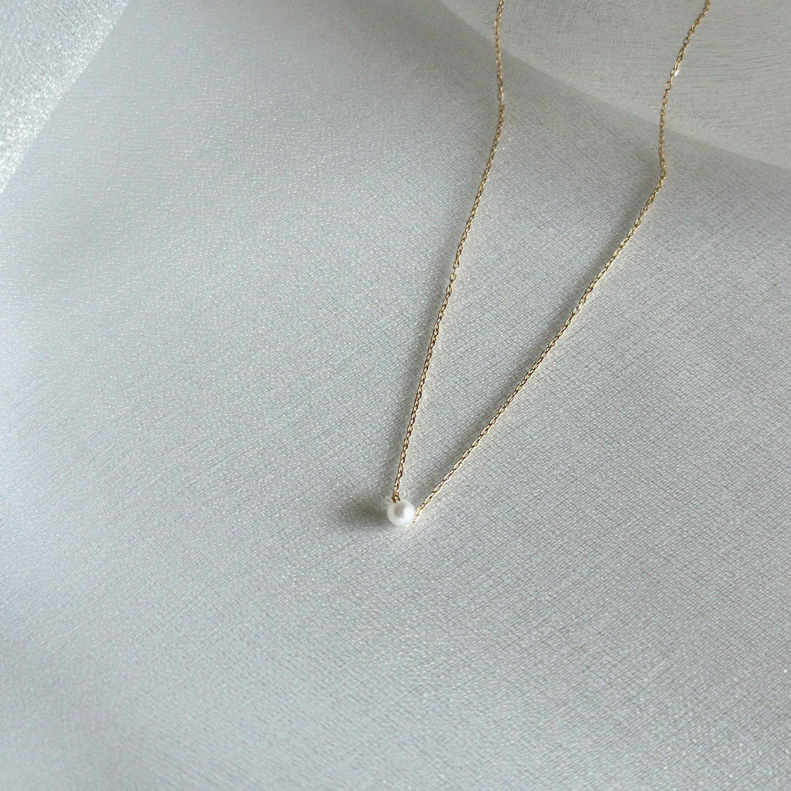 Side-angle view highlighting the pearl’s dimension and the chain’s sheen