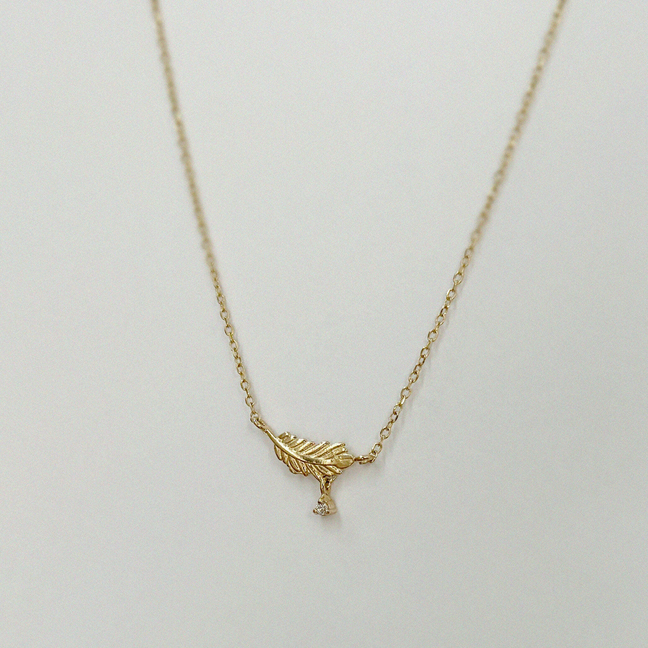 Ultra close-up of leaf-shaped pendant showing cubic zirconia sparkle and fine gold polish