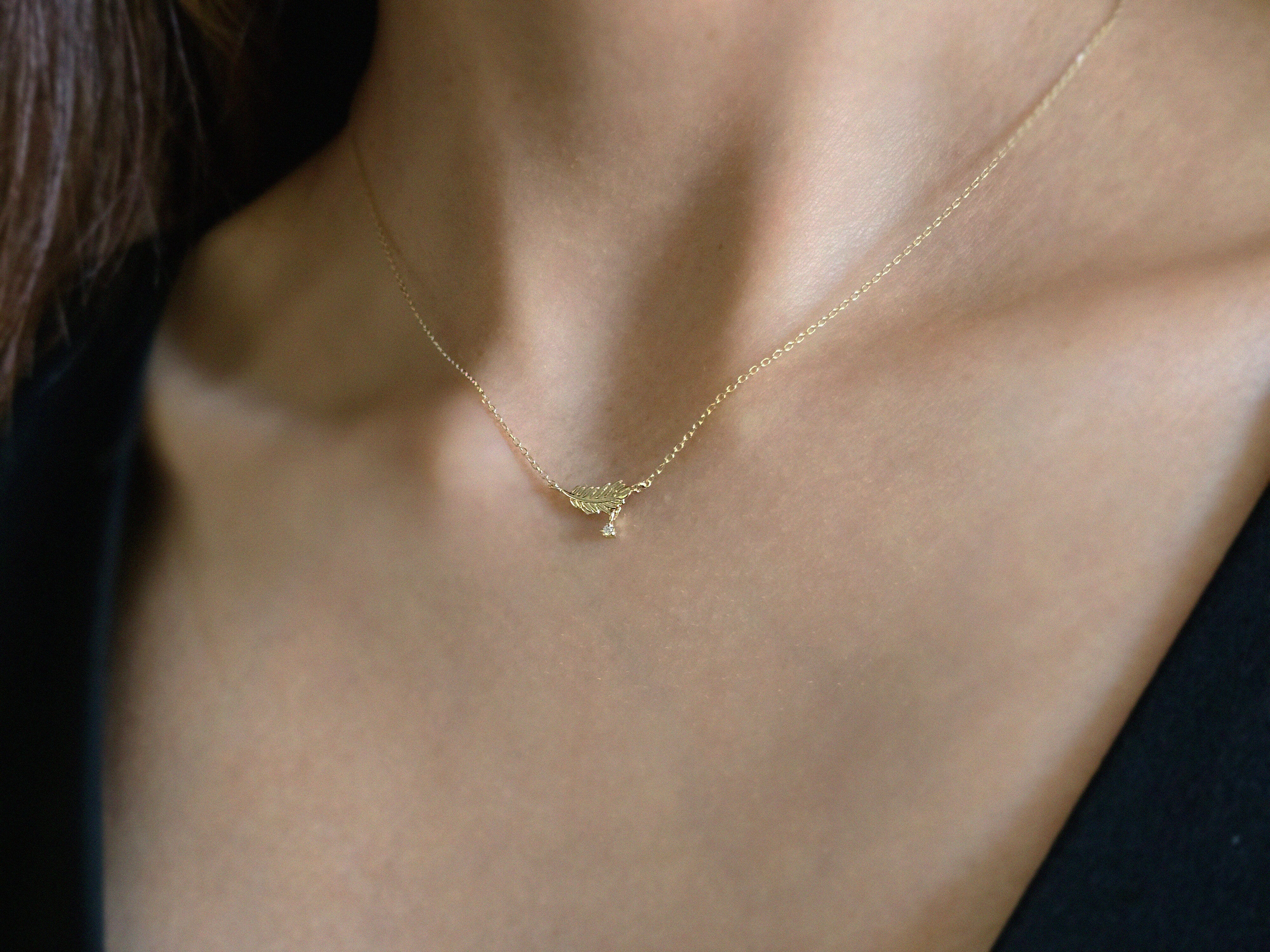 Gold leaf necklace styled for casual elegance on model’s collarbone