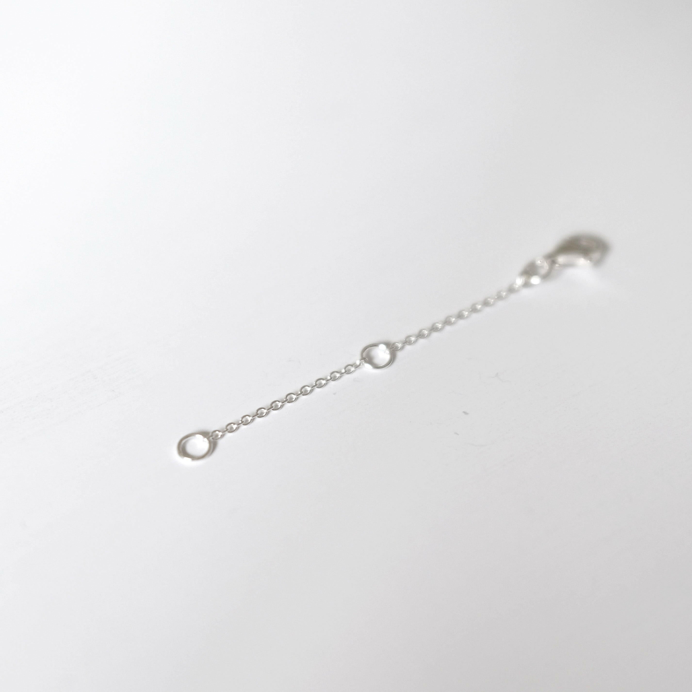 Macro shot of lobster clasp and O-ring connection on silver chain extender.