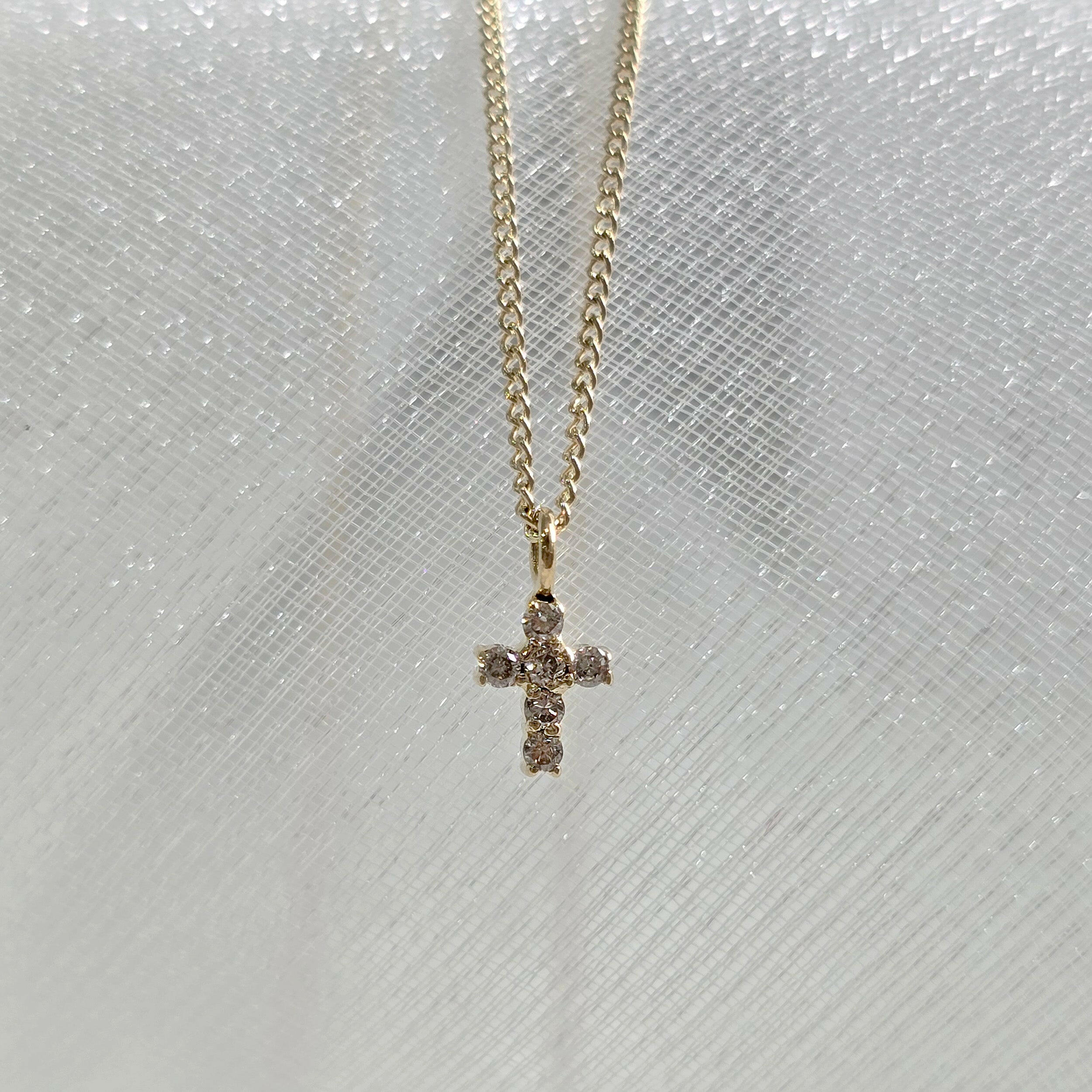 Overhead close-up of dainty diamond cross pendant – minimal and elegant