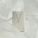 Diamond cross necklace displayed on soft leather necklace stand – balanced drape and elegant glow